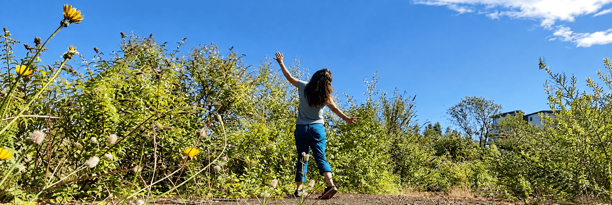 Person exploring expressive movement outdoors among wildflowers